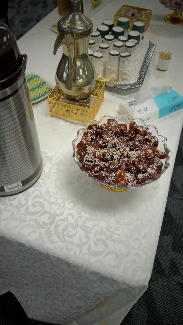 A coffee pot, cups and a bowl of dates on a hospitality table