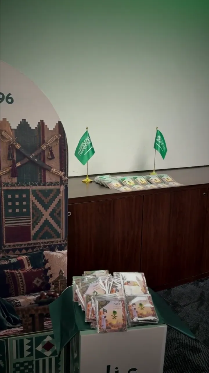 A heritage corner with Saudi flags and giveaway bags against a patterned backdrop