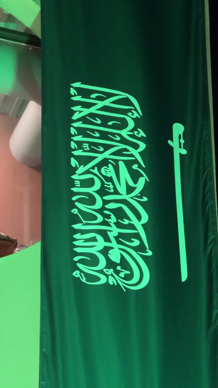 لقطة قريبة لعلم السعودية معلقاً على واجهة المحل