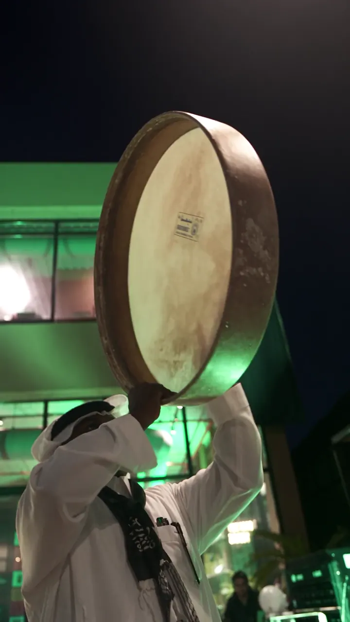 An Ardah drum in front of the lit facade
