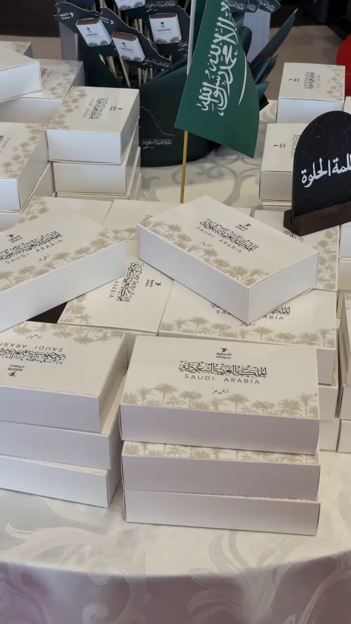 صناديق هدايا بيضاء مرصوصة مع علم سعودي صغير